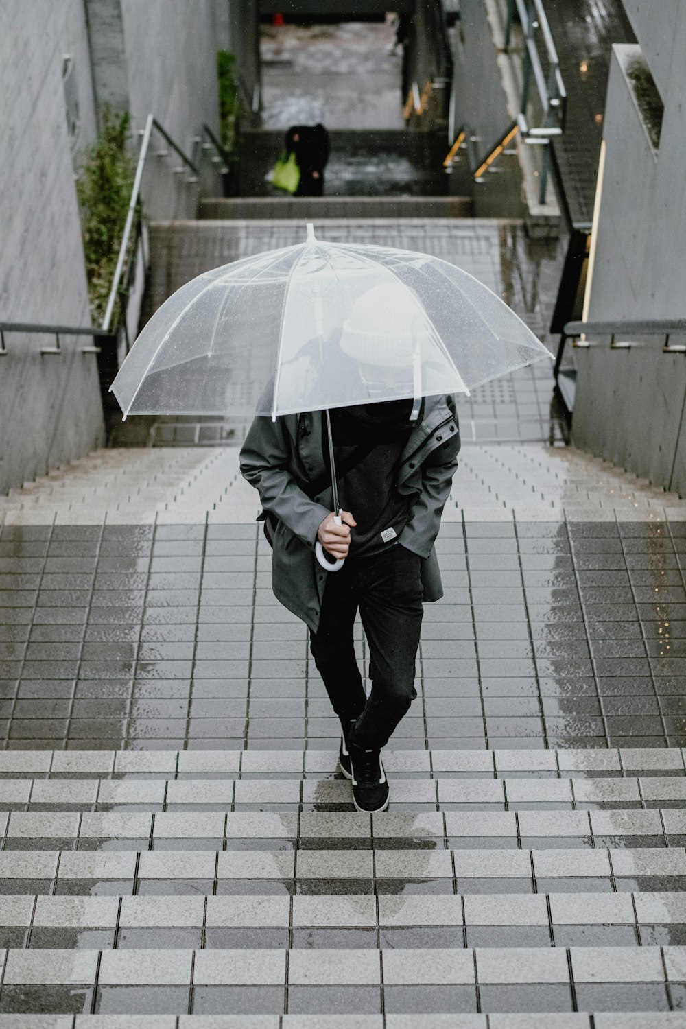 a man walking down a flight of stairs with an umbrella