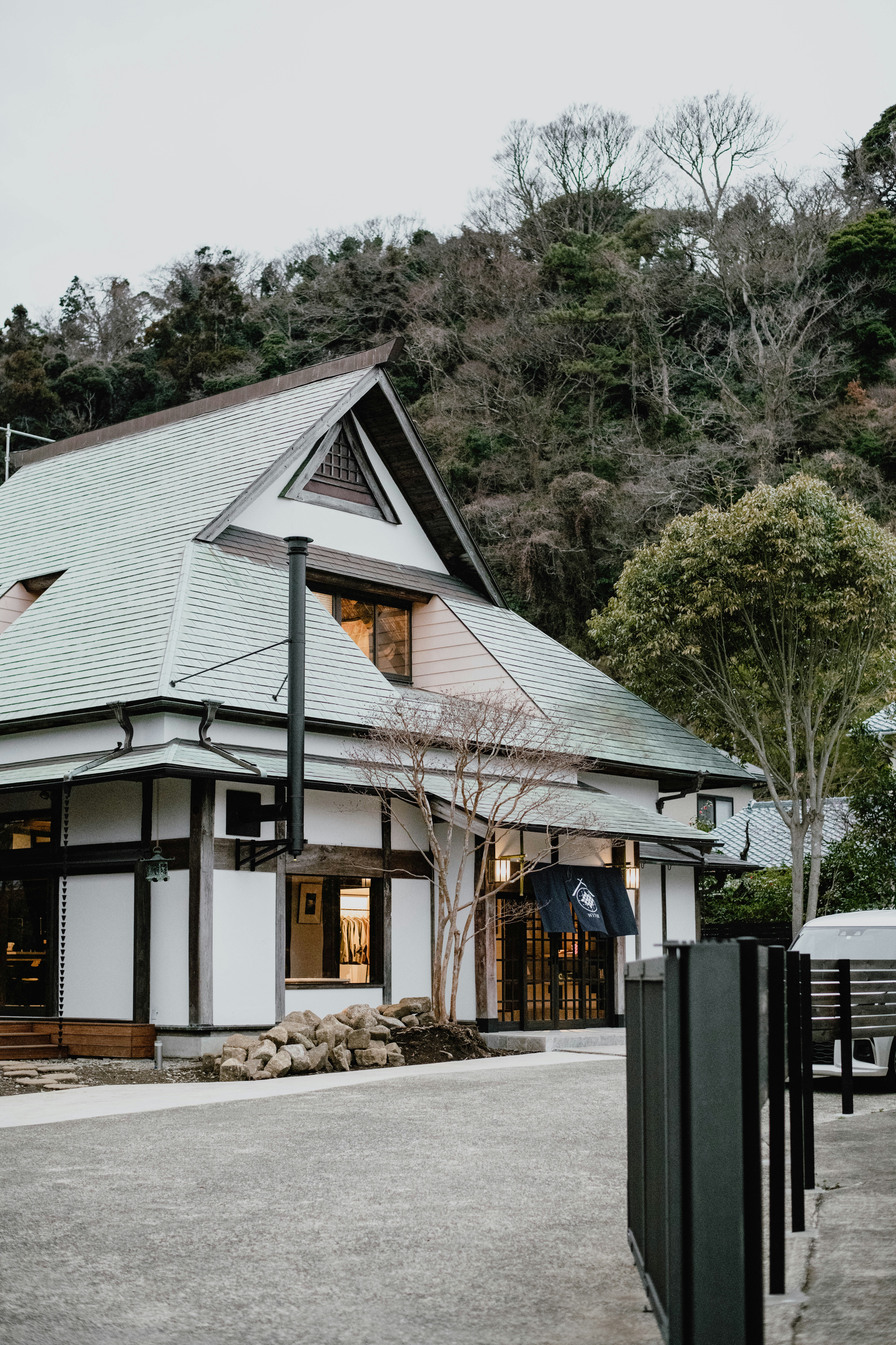 a white building with a black fence and trees in the background