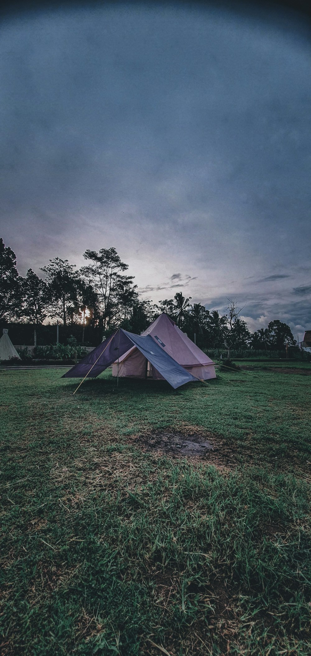 a tent pitched up in a field at dusk