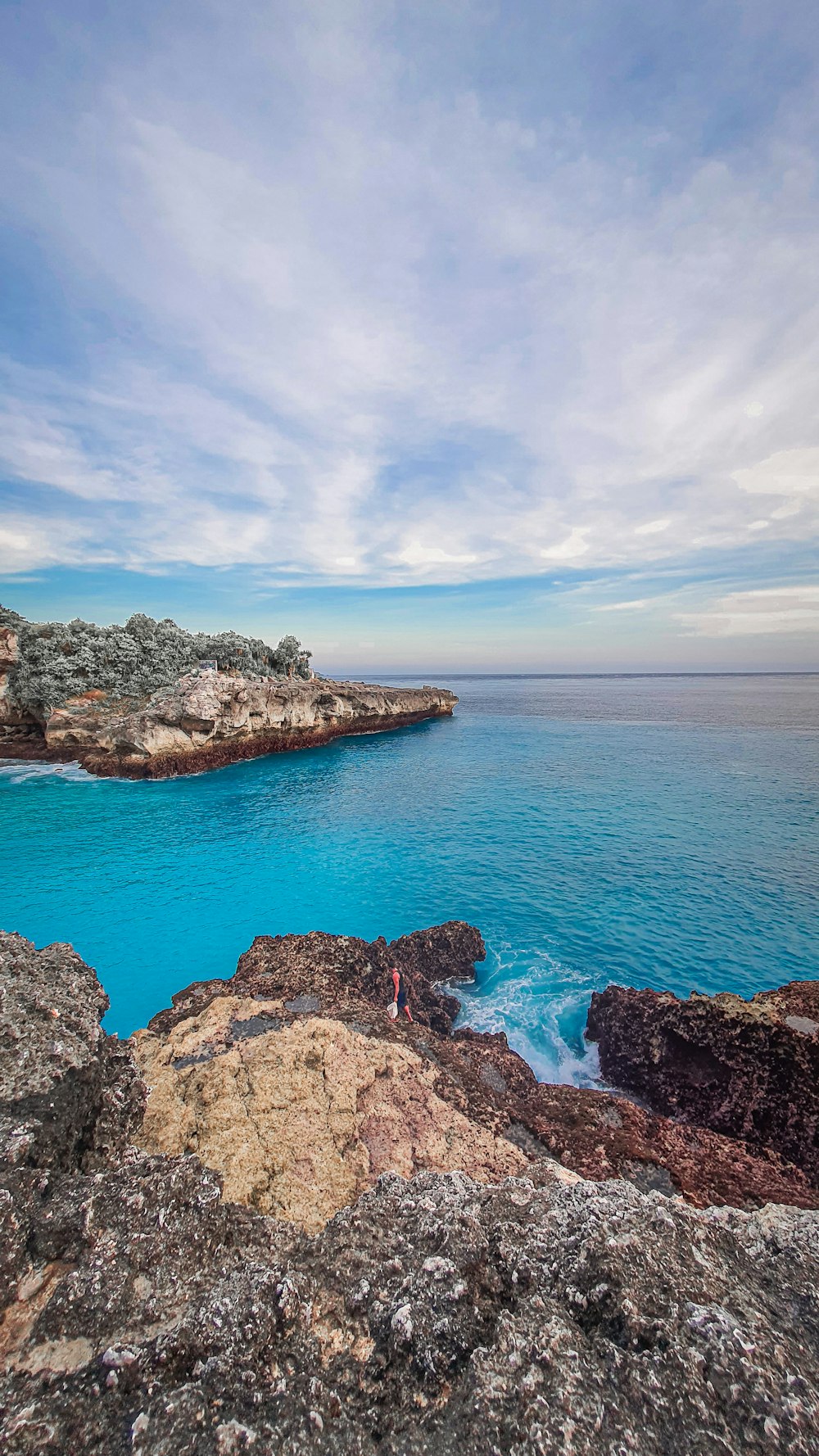 a couple of people standing on top of a cliff near the ocean