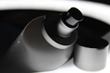Close-up of a glass spray bottle with a soft ivory background and charcoal accents.