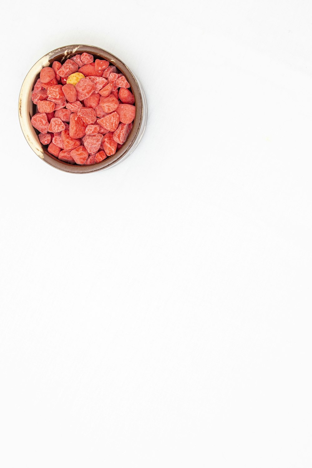 a metal bowl filled with red candies on top of a white table