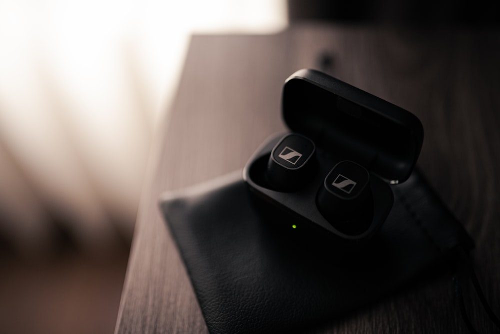 a pair of black earbuds sitting on top of a black case