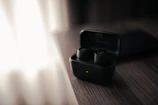 Sleek wireless earbuds resting on a minimalist wooden desk with soft natural light.