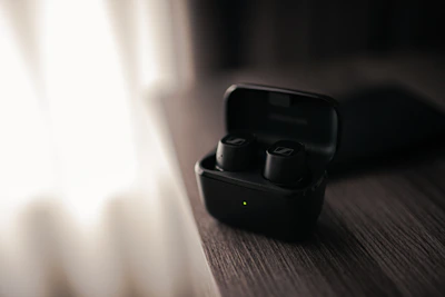 Sleek wireless earbuds resting on a minimalist wooden desk with soft natural light.