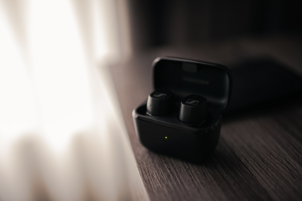 a pair of black earbuds sitting on top of a wooden table