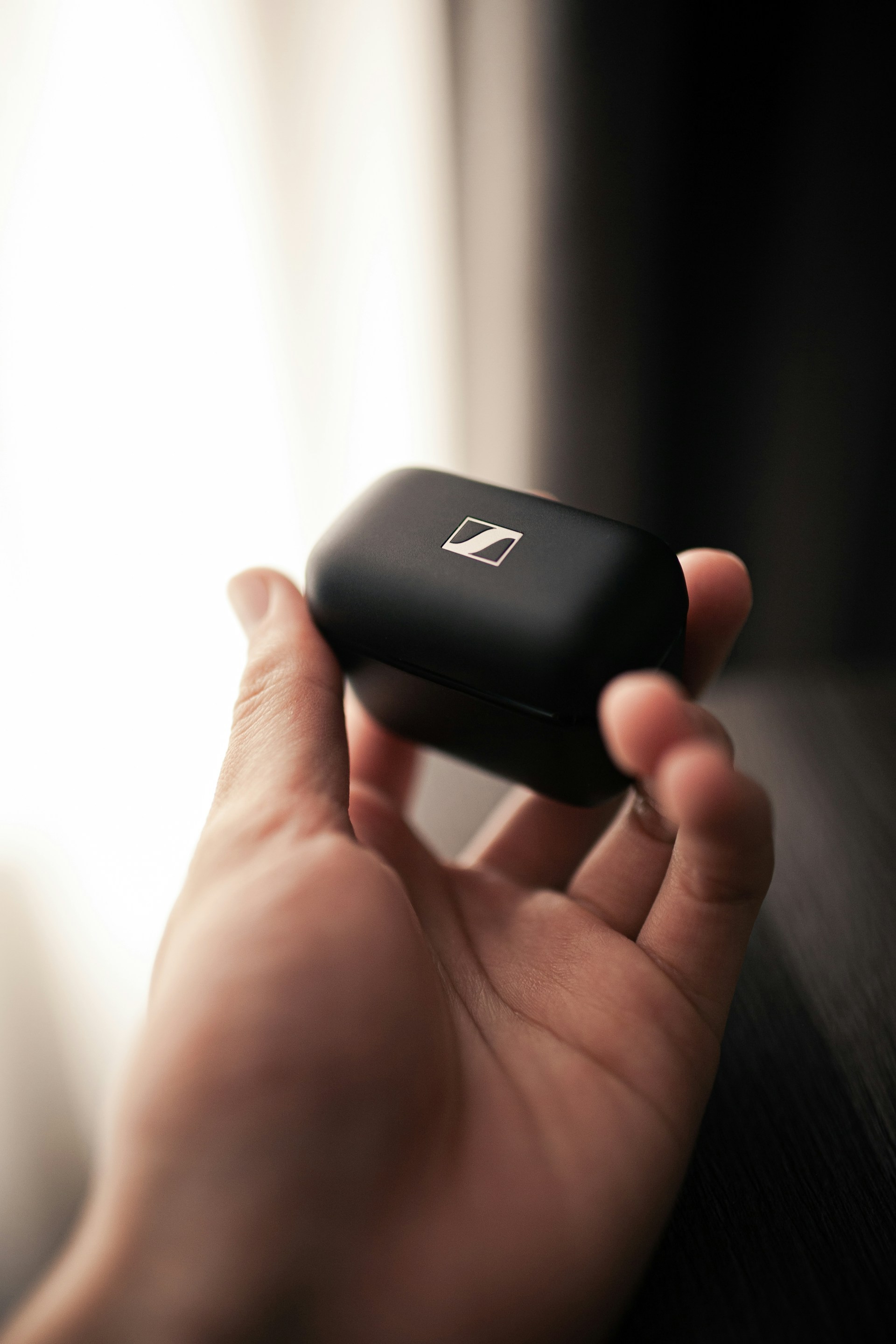 A detailed view of hands holding a sleek product against a neutral background.