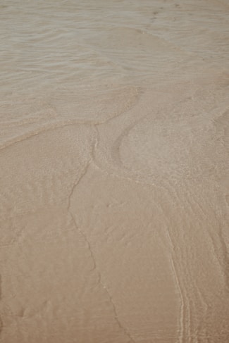a person riding a surfboard on top of a sandy beach