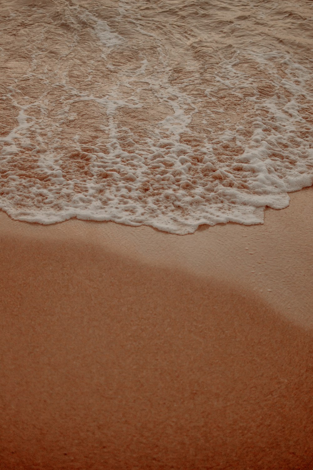 a sandy beach with waves coming in to shore