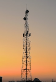 Microwave antenna tower set against a clear sky at sunset.