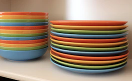 Stacks of colorful children's tableware ready for packaging in a clean, modern factory setting.