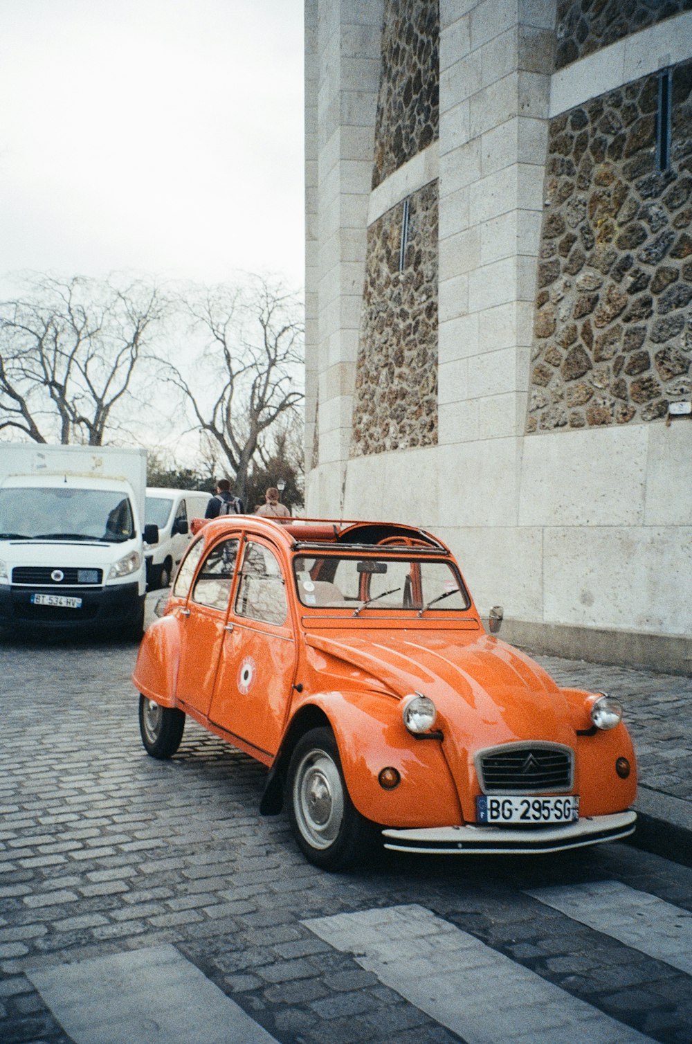 an orange car is parked on a cobblestone street