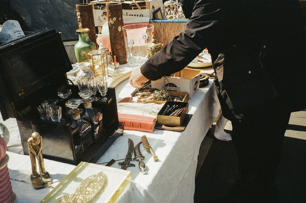a man standing over a table filled with lots of items