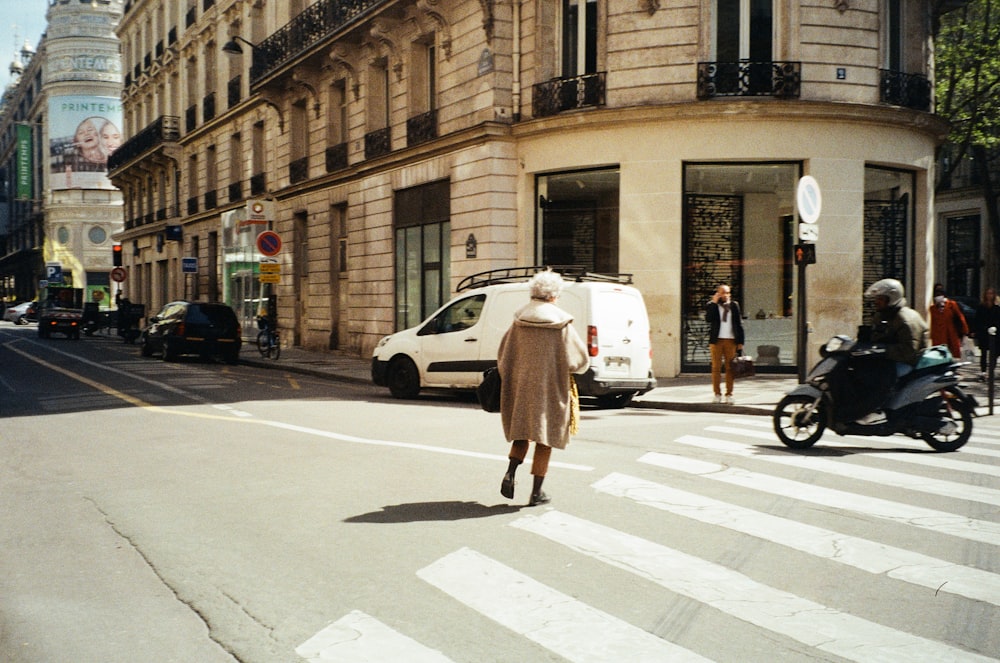 a woman walking across a street next to tall buildings