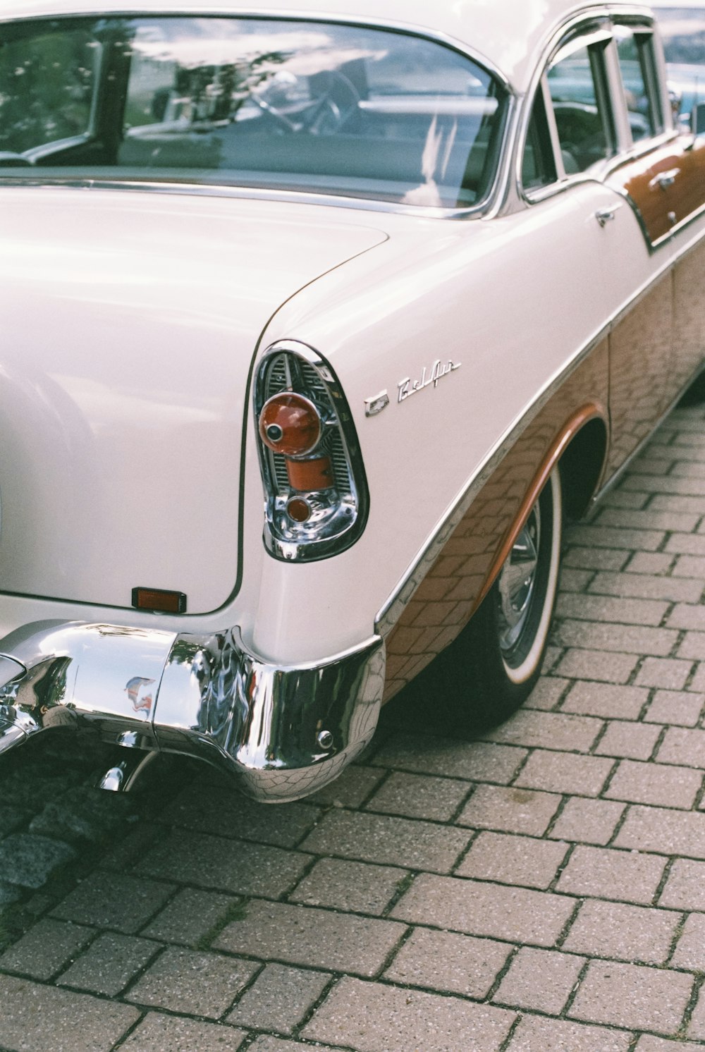 a classic car parked on a brick sidewalk