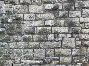 Close-up of a skilled mason carefully laying natural stone on a rustic wall at a sunny Arles construction site.