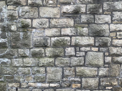 Close-up of a skilled mason carefully laying natural stone on a rustic wall at a sunny Arles construction site.