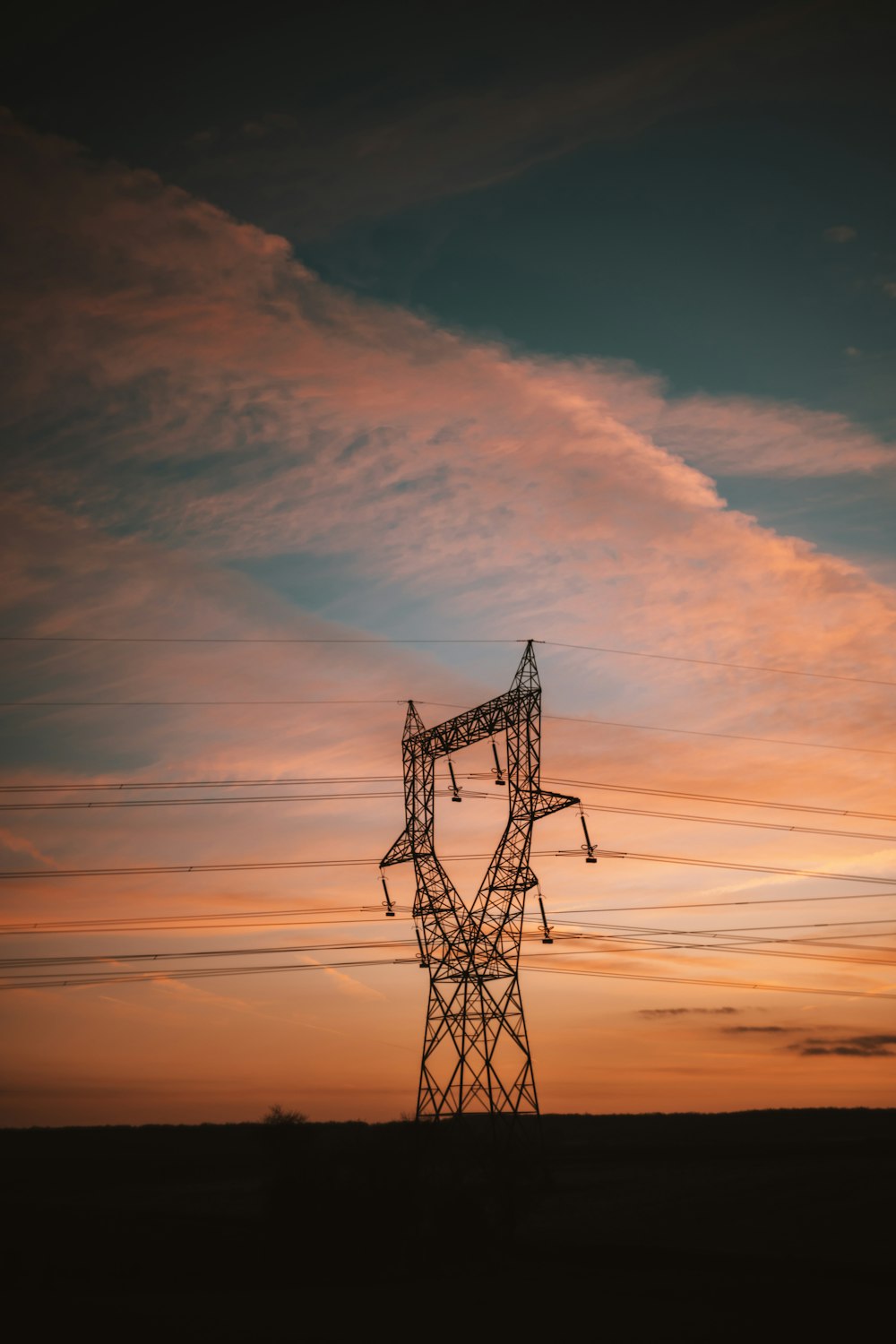 a power line with the sun setting in the background