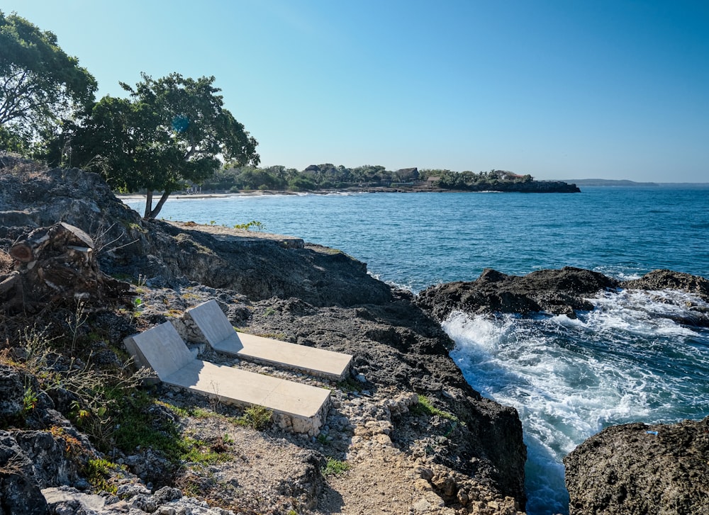 Un par de sillas sentadas en la cima de una playa rocosa