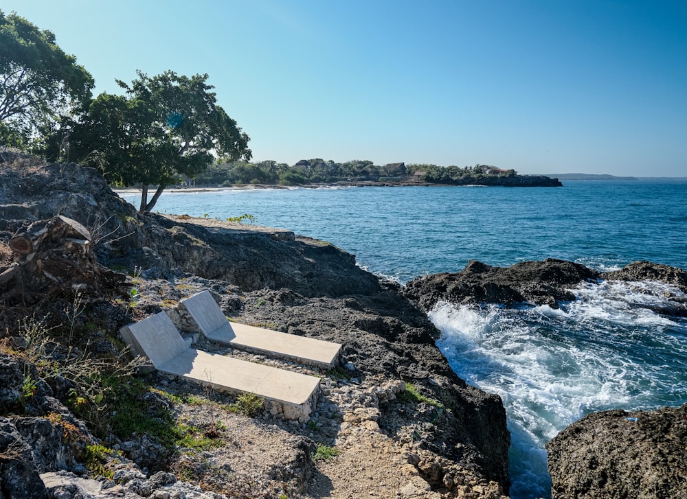 a couple of chairs sitting on top of a rocky beach