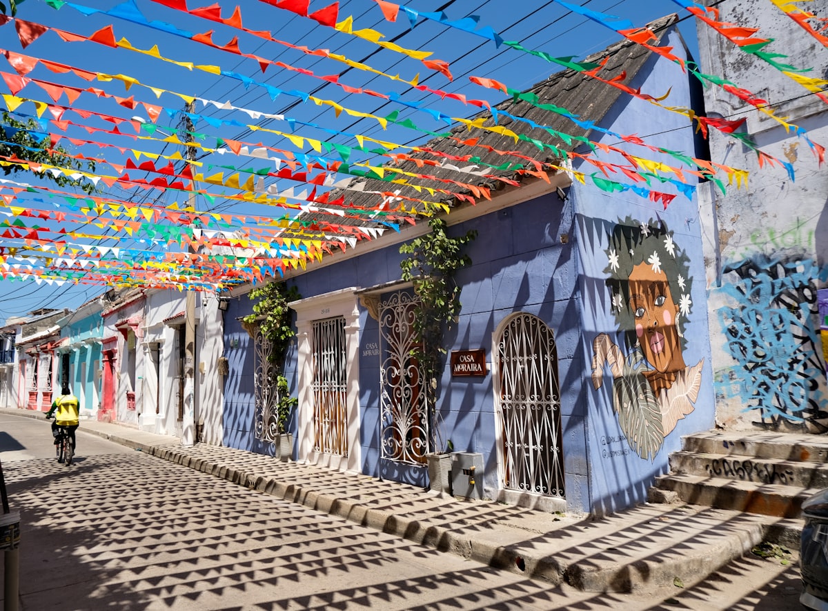 Cartagena November — a Getsemaní street with hundreds of colourful paper flags strung overhead and painted street murals on the walls