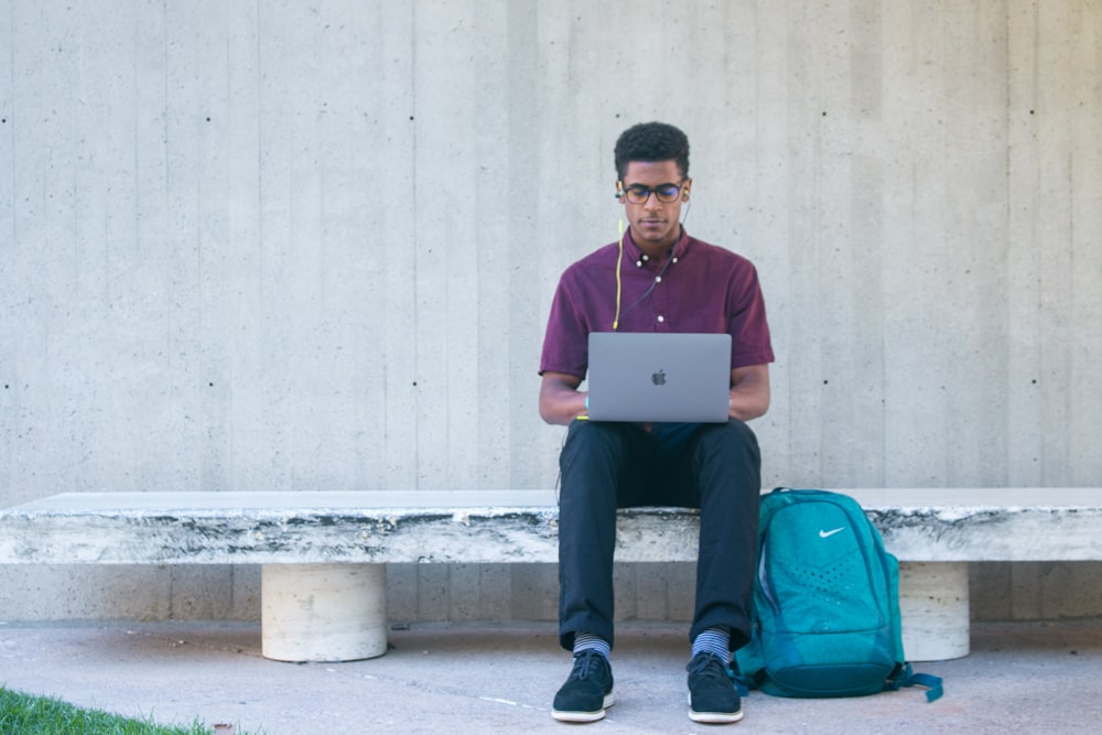 a man sitting on a bench with a laptop