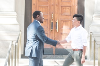 two men shaking hands in front of a door