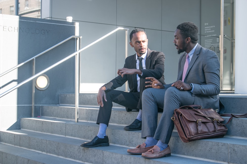 a couple of men sitting on top of a set of stairs