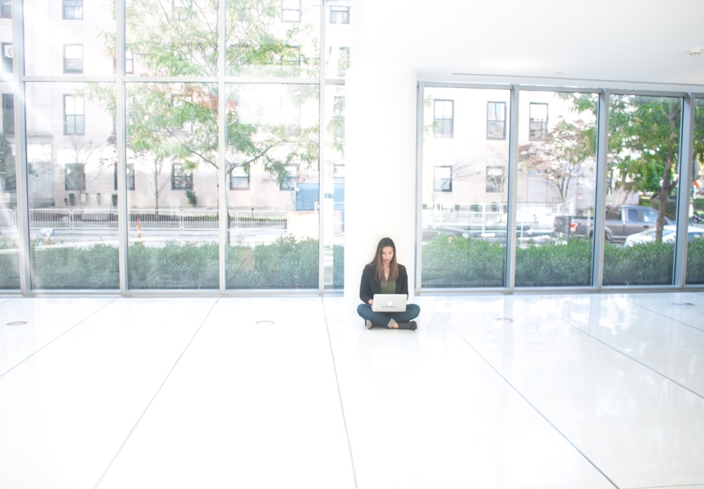 a woman sitting on the floor with a laptop