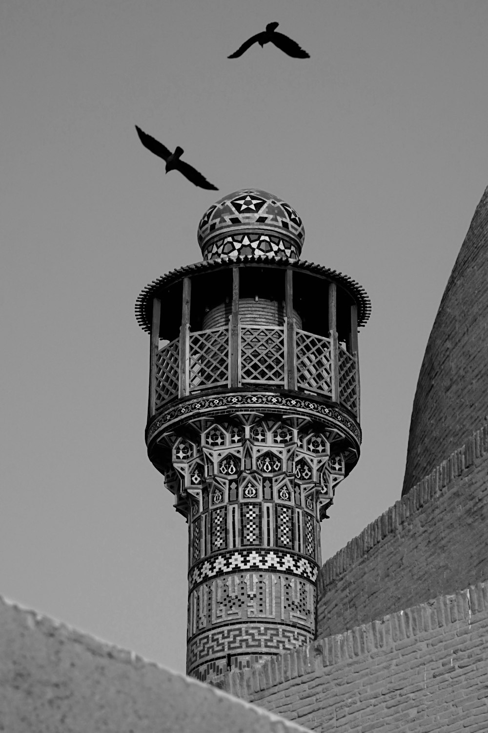 two birds are flying over a tall tower
