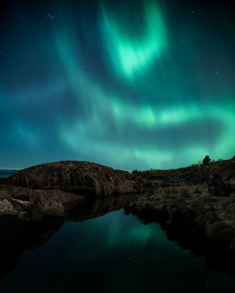 the aurora bore is reflected in a body of water