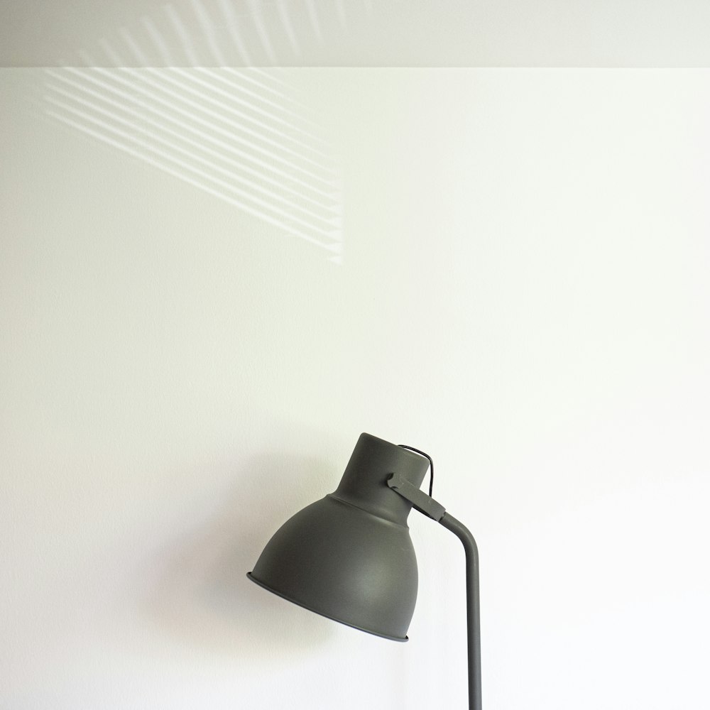 a black lamp sitting on top of a white wall