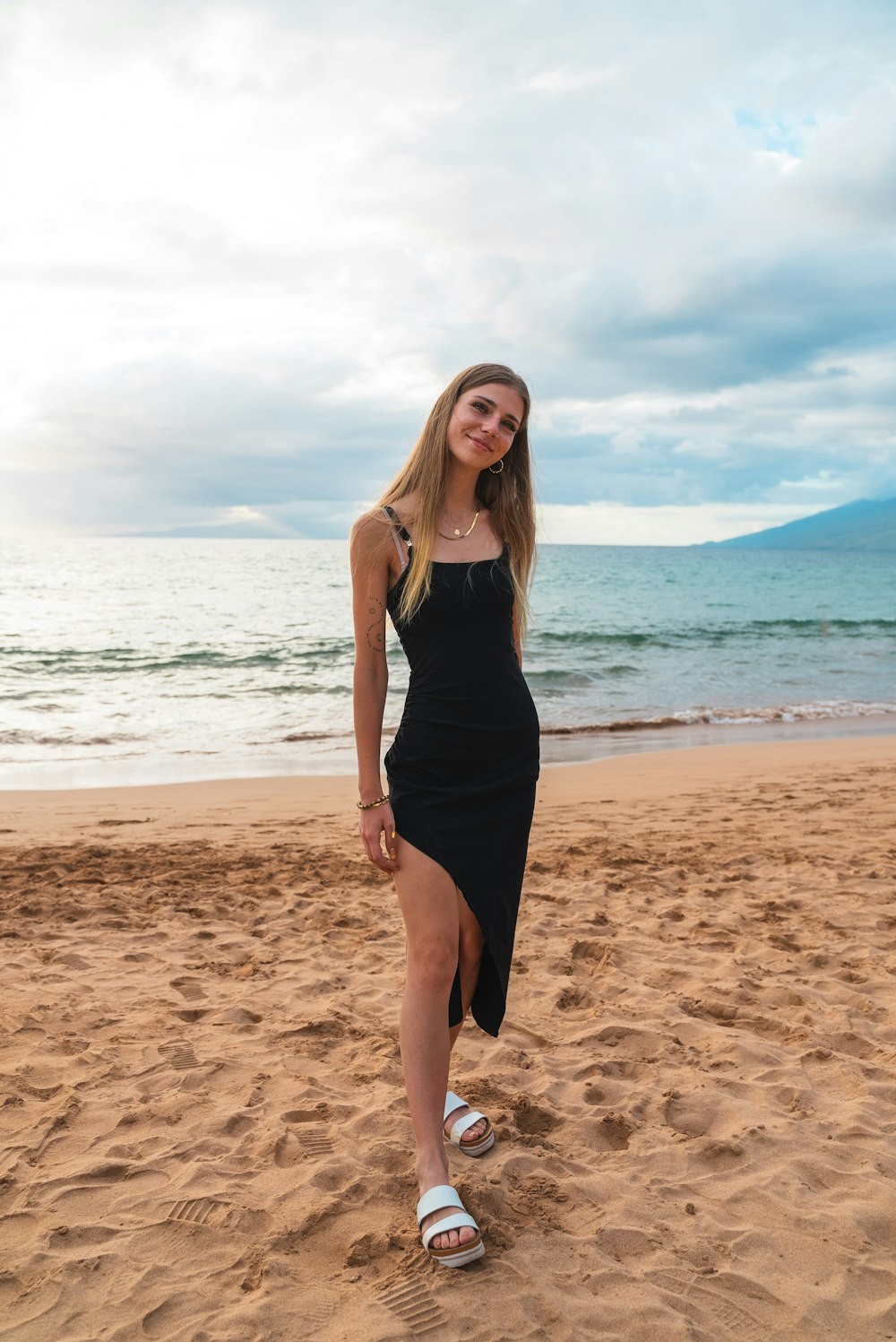 Una mujer parada en la cima de una playa de arena