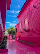 a pink house with a red roof and a pink walkway