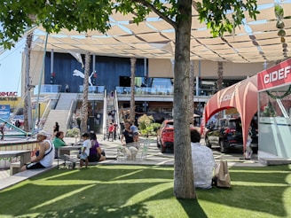 Modern shopping mall exterior with people walking nearby on a sunny day