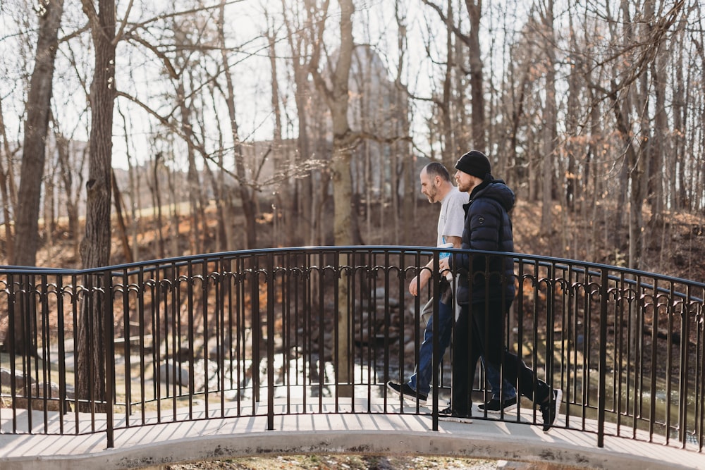 a couple of men walking across a bridge