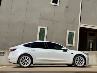 A sleek white sedan parked in front of a modern office building in Abu Dhabi.