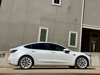 A sleek modern car parked outside a rental office during the day.
