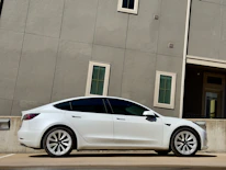 A sleek car parked in front of a modern office building on a sunny day.