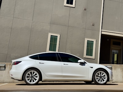 A sleek white sedan parked in front of a modern office building on a sunny day.