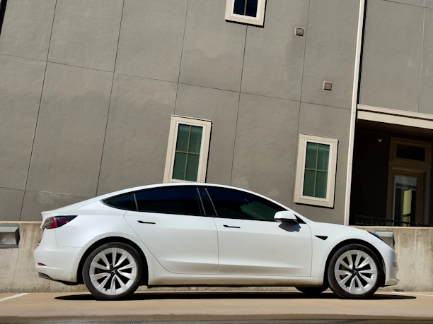 A sleek, modern car from the rental fleet parked in front of a city building on a sunny day.