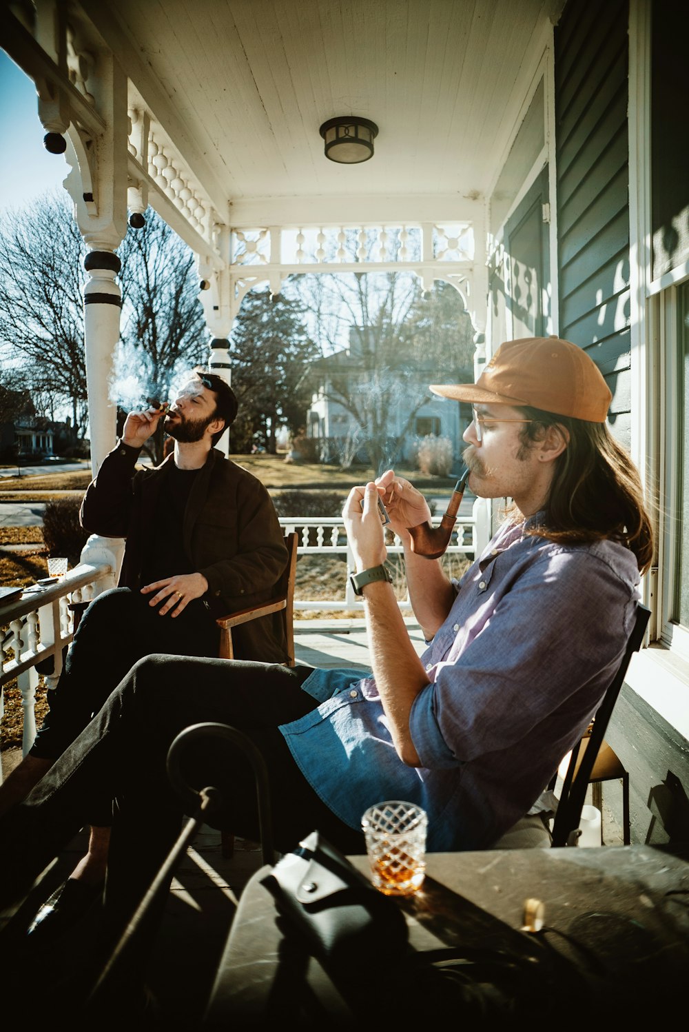 a man sitting on a porch smoking a cigarette