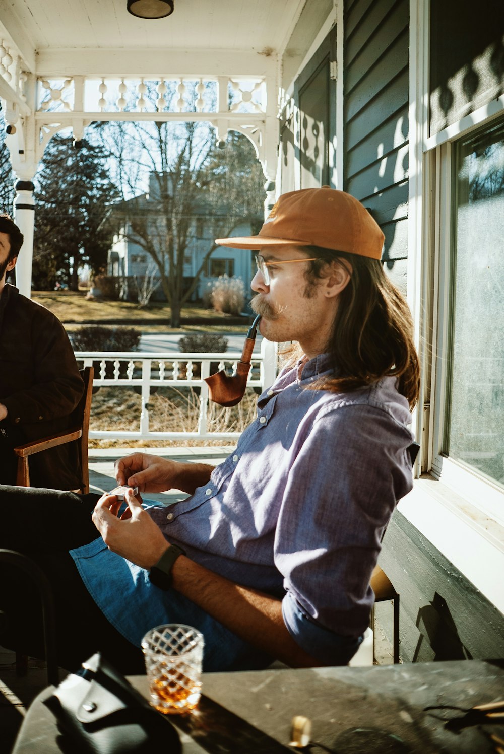 a man sitting on a porch with a pipe in his mouth