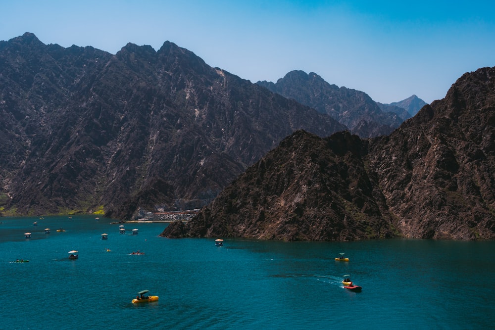 a group of boats floating on top of a lake surrounded by mountains