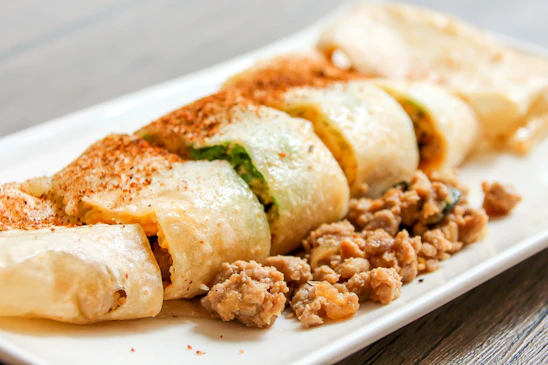 Close-up of a juicy kathi roll with vibrant fillings, placed on a rustic wooden table.