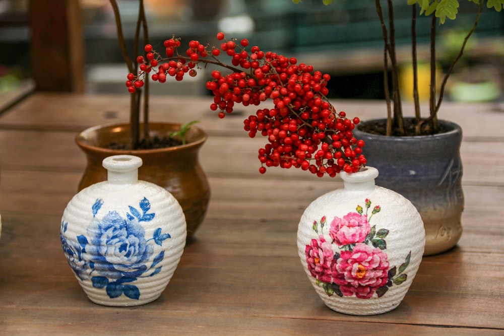 three vases with flowers painted on them sitting on a table