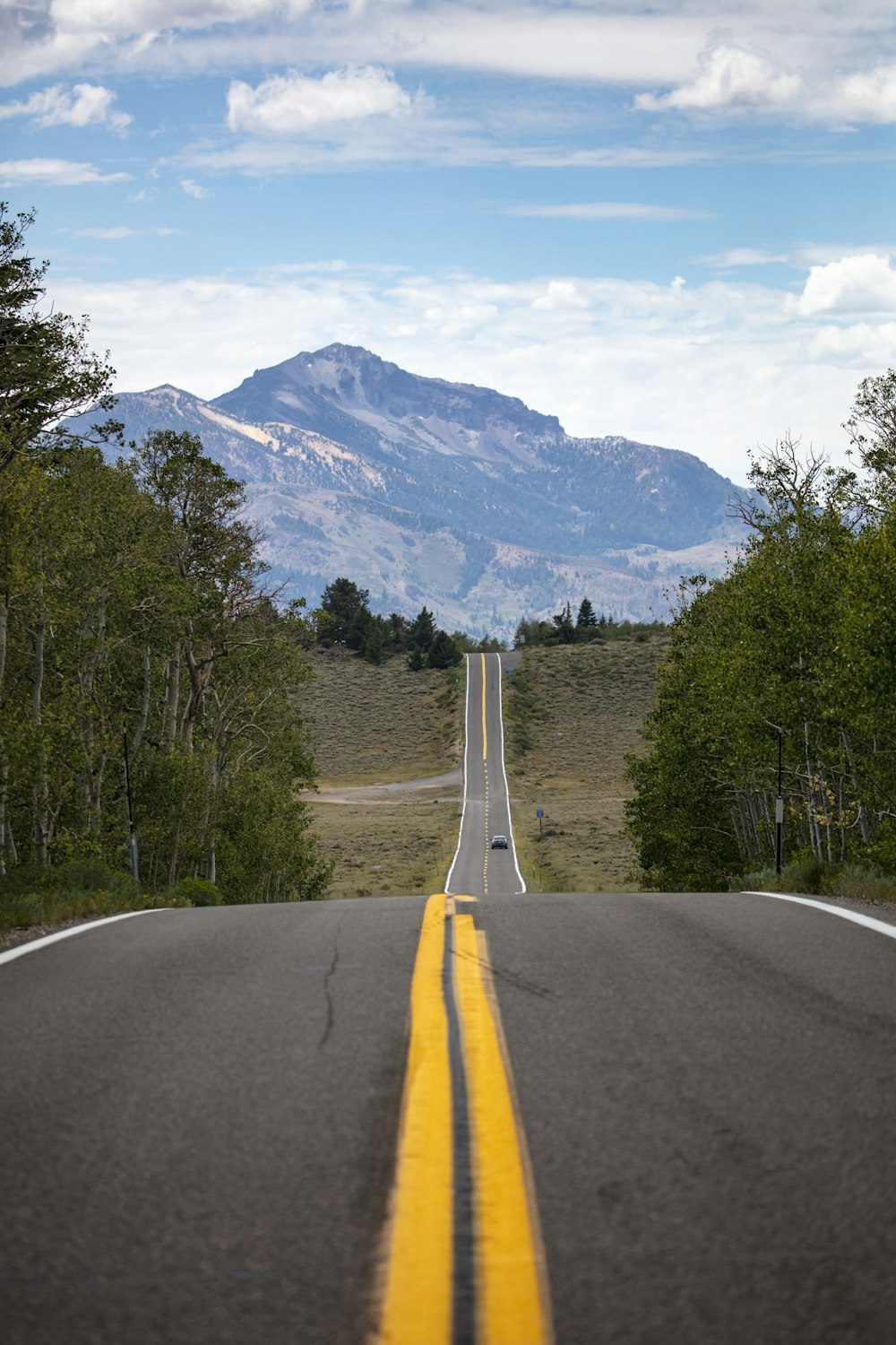 a long straight road with a mountain in the background
