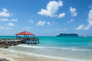 a pier with a boat in the background and a cruise ship in the distance