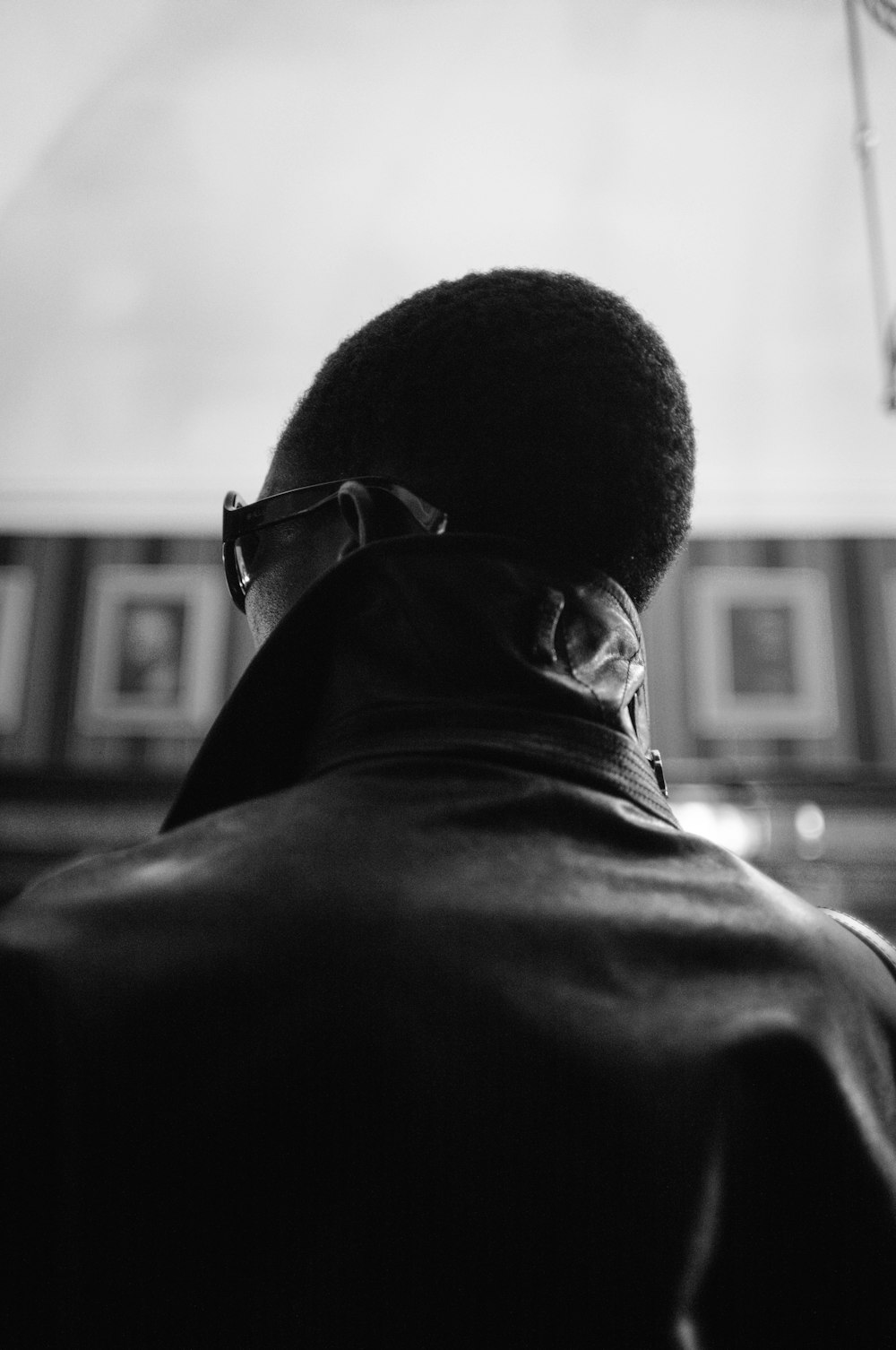 a man in a leather jacket looking out a window