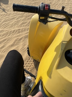 Close-up of a rider’s hands gripping the quad handlebars with desert landscape blurred behind.